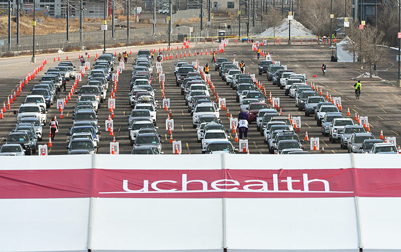 Cars lined up at a mass vaccination event in a parking lot at Coors Field.