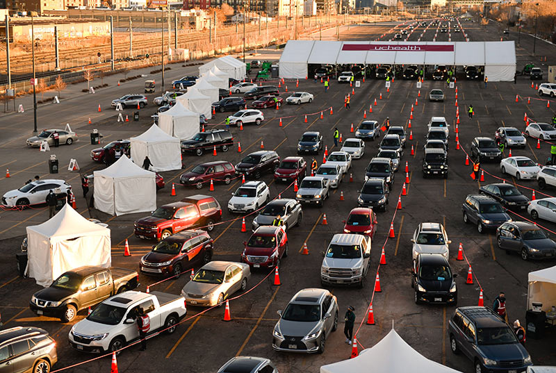 The sun rises and bounces off cars lined up for a mass vaccination event.