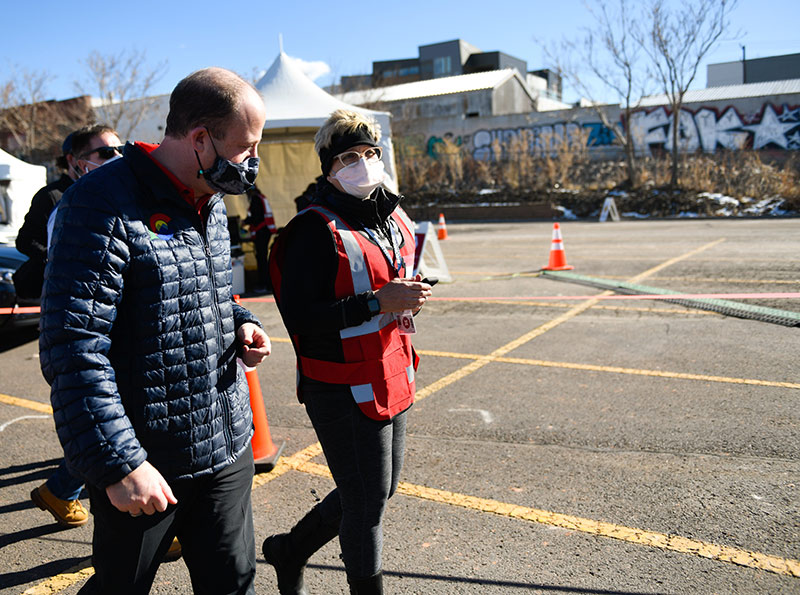 Gov. Jared Polis speaks with a UCHealth worker during a mass vaccination event on Saturday, Jan. 30 at Denver's Coors Field.