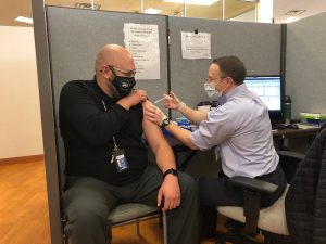 Paul Yenne, a fifth grade teacher at Steele Elementary School, receives a vaccine from Dr. Donald Setter, a UCHealth family practice physician.