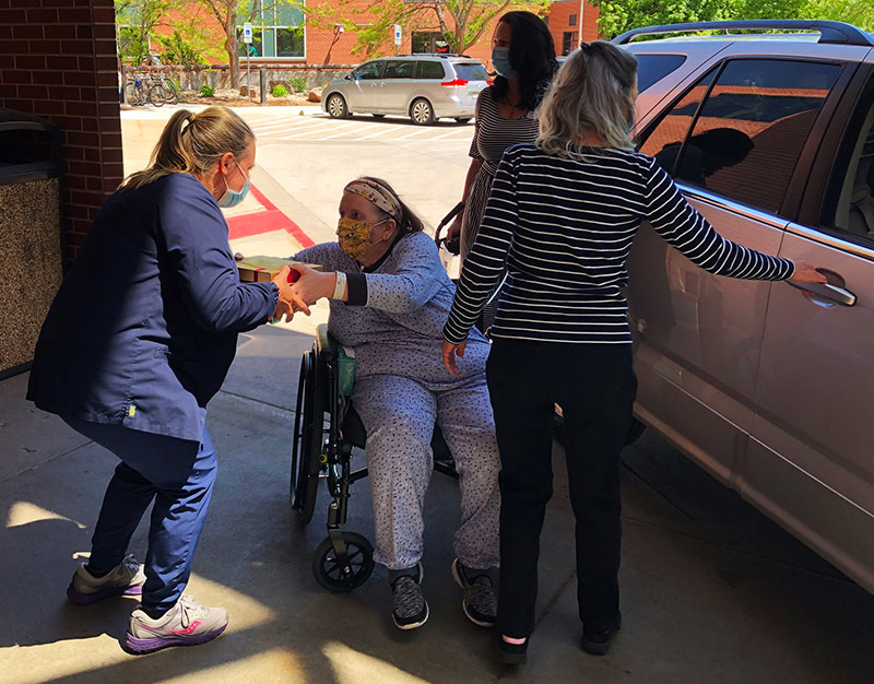 Deb Hoffman hands a box of cookies to a nurse at UCHealth Poudre Valley Hospital just before getting in her sister's car to go home. Deb spent 49 days in the hospital, three weeks which were at PVH to rehabilitate to life after COVID-19