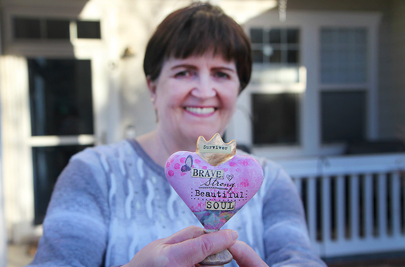 Deb Hoffman holds up a "survivor" heart she got from her family as she talks about her life after COVID-19.