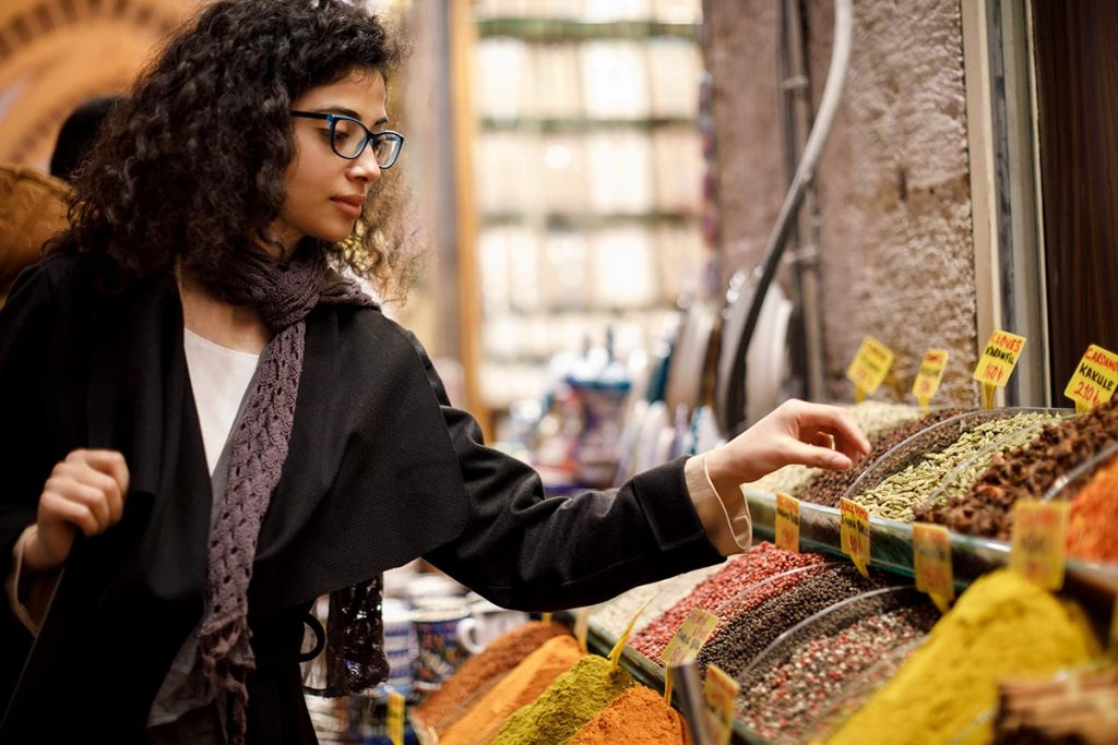 A woman selects spices from a market for Indian cooking.