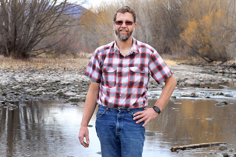 Wade L Clements, who benefited from occupational health services that UCHealth provides employers, stands in front of a river.