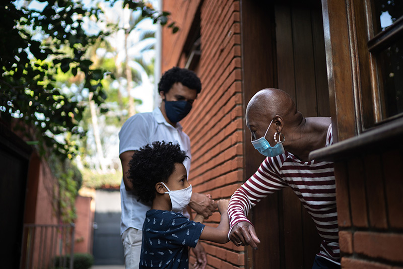 What's safe after vaccine? Here, a grandmother wearing a mask greets her grandson.