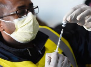 man readying a covid vaccine in an effort to achieve herd immunity.