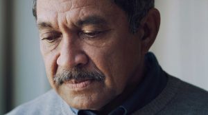 Breakthrough symptoms of COVID-19 can be milder than original COVID-19 infections. Here a Latino man looks serious.
