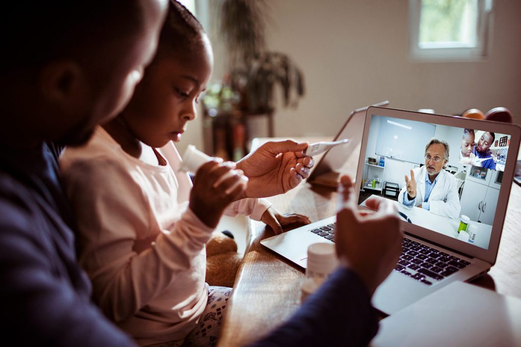 A man and a child visit with a medical provider virtually.