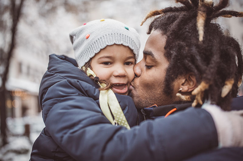 father kisses his daughter. In an effort to keep her healthy and safe, UCHealth provides some winter health tips.