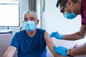 nurse gives man a vaccine, helping him make sense of covid boosters and when he should get one.