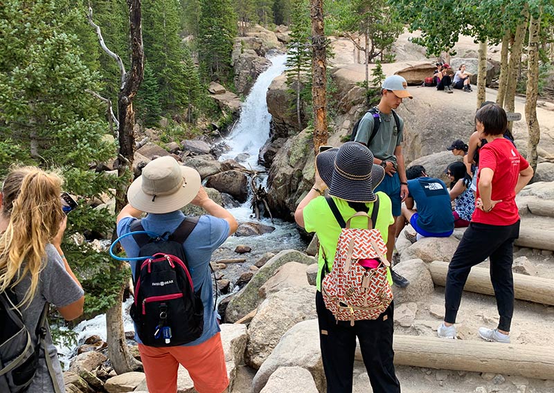 A crowd gathers to take photos at Alberta Falls in Rocky Mountain National Park. Photo by Cyrus McCrimmon for UCHealth.