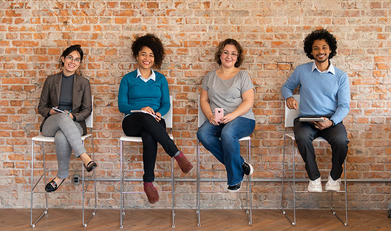 four people of different ethnic backgrounds sitting on chairs. Ethnicity and family history play a part in your risk for diabetes.