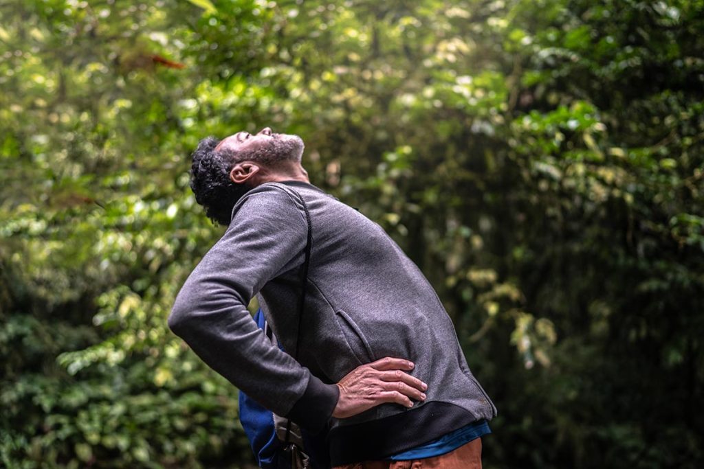 Mature man in the forest exercising which helps him maintain a healthy spine.