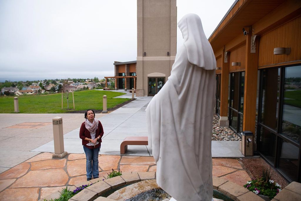 Anna Salvador pauses to pray before a statue of the Virgin Mary.