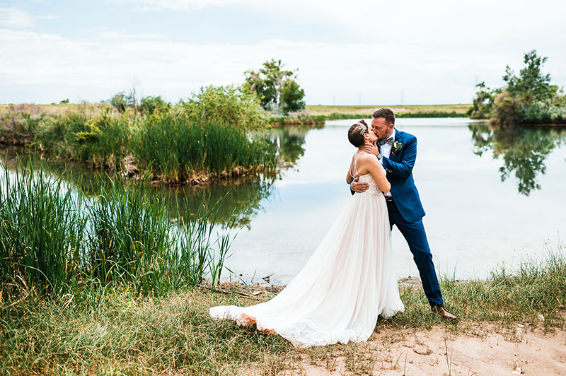 Mal Foust and Jess Wheeler kiss in front of a lake at their wedding. Photo courtesy of Mal Foust.