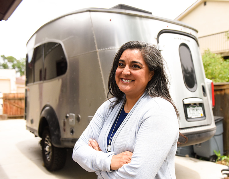 A la Dra. Abbey Lara le encanta acampar y cazar. Aquí, posa con el remolque de viaje Airstream que ella y su esposo compraron durante la pandemia. Foto de Cyrus McCrimmon para UCHealth.