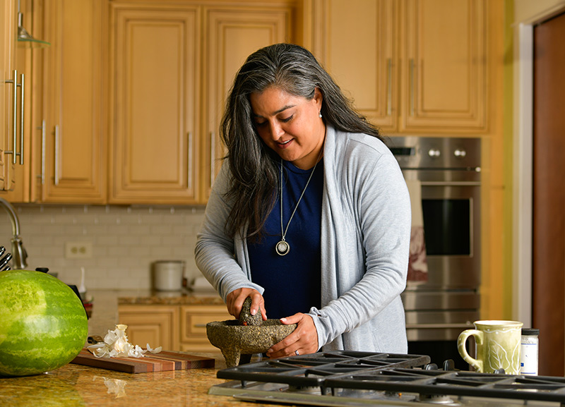 A la Dra. Abbey Lara le encanta cocinar para los demás. Una de sus especialidades es su salsa verde. Ella usa el molcajete de su abuela para moler los chiles. Foto de Cyrus McCrimmon para UCHealth.