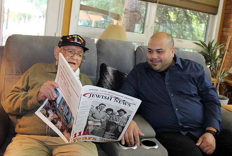 For Bernie Rogoff, 95, and Michael Foresman, 34, a strong friendship has grown thanks to a program, which pairs students in health care professions with older community members. Michael is studying to become a pharmacist, and Bernie served as a medic during the Korean War. In this photo, Bernie shows him a profile of his life published by the Jewish News and shares his experiences as a veteran. Photo by Ana Gretchen Robleto, UCHealth.