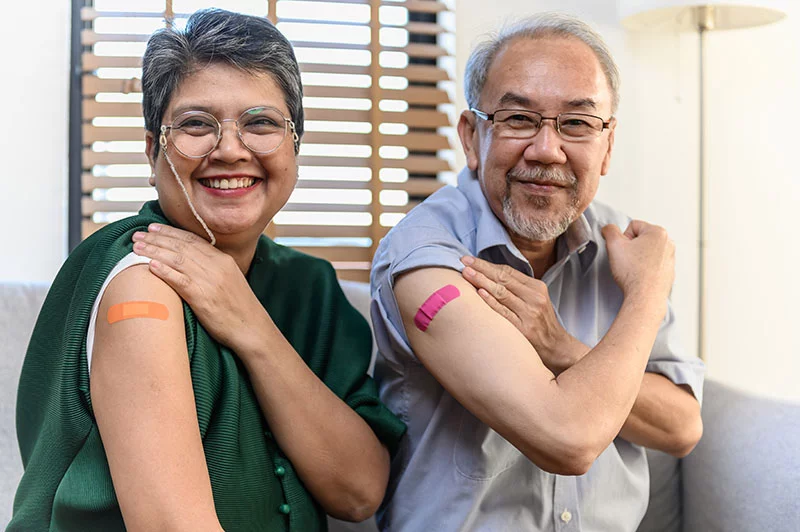 Two people showing off their Band-Aid were they got their vaccines. Getting your updated 2025-26 COVID-19 and flu vaccines soon can help protect you from serious illness this fall and winter. Photo: Getty Images.