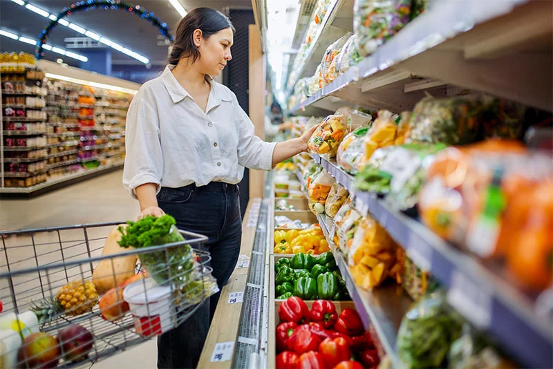 Woman shopping for produce at the grocery store. Fresh fruits and vegetables are an important part of a healthy diet. Washing produce thoroughly can help reduce the risk of foodborne illness. Photo: Getty Images.