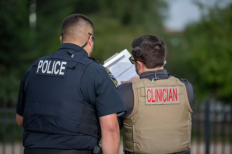 Police officer, left, and behavioral health expert. Patrick Drossel, right, wears a vest that identifies him as a behavioral health expert when he's working with his police partner, Geno Gonzales. When people are experiencing crises, Drossel takes the lead to provide them with necessary support. Photo by Chuck Bigger, for UCHealth.