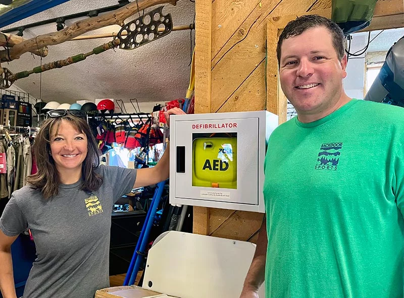 Mike Welch and Dominique Welch, two of the co-owners of Backdoor Sports, install their AED cabinet in Backdoors Sports Tuesday morning. Photo: UCHealth.