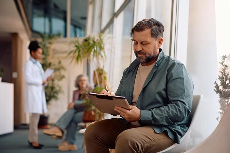 Man fills out insurance information at a doctor's office. Understanding what UCHealth facilities and hospitals are in-network for your plan is important. Photo: Getty Images.