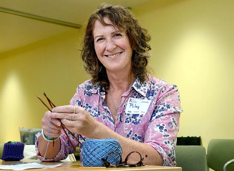 Riley Mulligan starts a knitted prostheses in her tenth Knit-a-thon. She recently marked two years after her first breast cancer surgery. A good friend made Knitted Knockers for her, which she used for a year before reconstructive surgery. She described the pair as lightweight and soft, not heavy and hot like a prosthesis. "It gave me a sense of my femininity back when I was going through my journey," she said. Riley is a palliative care nurse navigator at UCHealth Harmony Cancer Center. Photo by Sonya Doctorian, UCHealth.