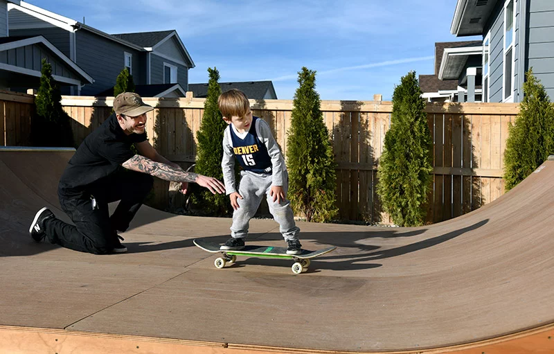 Colin offers a helpful push to his son, Will, 4, to begin his slow ride up the curved wall of the backyard mini halfpipe. "What do you do if you fall?" he asked Will later. “Get up!” Will said. Photo by Sonya Doctorian, UCHealth.