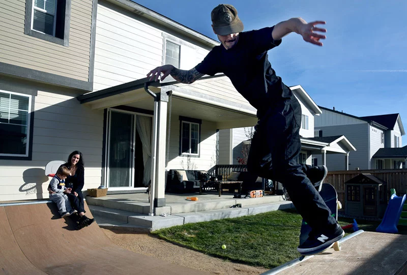 Colin Kiesel on his backyard mini half pipe as wife Natasha watches with son Will, 4, on Sunday, Nov. 9. “To see how far he's come is incredible,” she said. Natasha contacted a friend in California with her idea of building a mini half pipe in their backyard last year. Several longtime California skateboard friends raised money to buy the materials. Three friends drove it out from California, surprised her husband,and built it. Natasha said, “I know how much skateboarding means to Colin.” Photo by Sonya Doctorian, UCHealth.