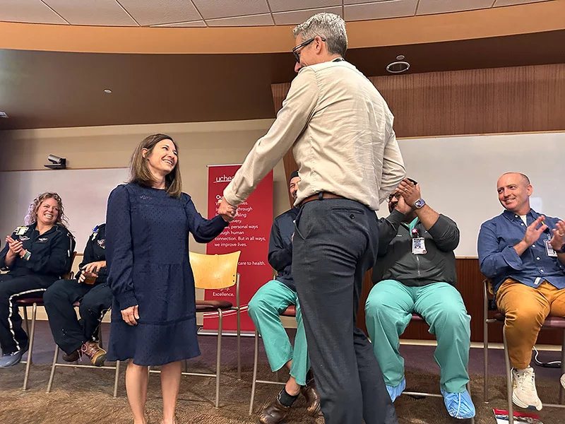 Amy Davis shakes hands with her neurohospitalist, Dr. Brian Kaiser, during a medical education event at UCHealth Medical Center of the Rockies about six months after her stroke. Also pictured, from left, is flight nurse Joylyn Godinezy and flight paramedic Autumn Kenney, who transported her from UCHealth Estes Valley Medical Center to Medical Center of the Rockies, trauma surgeon Dr. Christopher Mitchell, Dr. Gautam Sachdeva, who performed her thrombectomy, and physical therapist Tim Koblenz. Photo by Kelly Tracer, UCHealth.