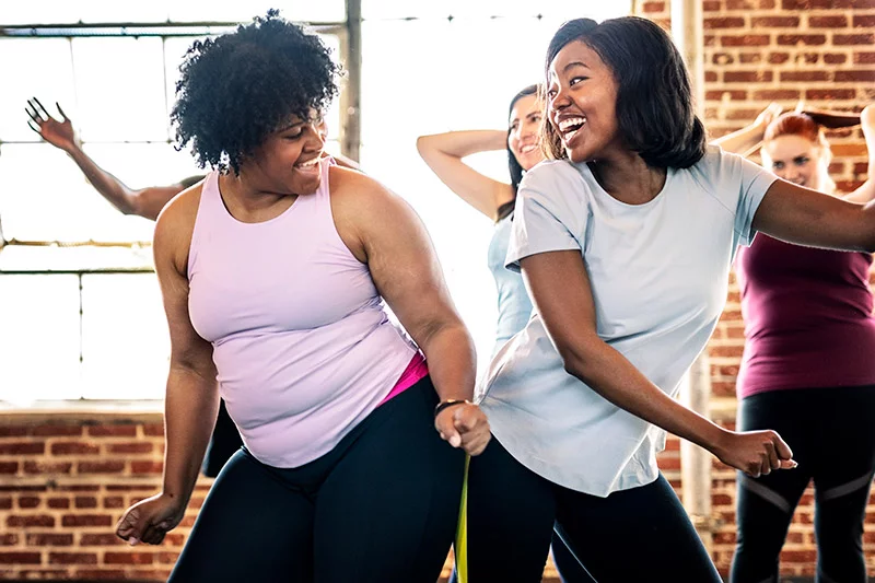 Two woman having fun during a workout class. Photo: Getty Images.
