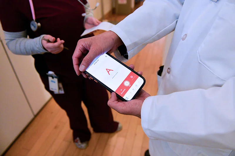 Dr. CT Lin holds a smartphone showing Abridge, a tool which records and transcribes clinic visits. Abridge allows providers to focus solely on patients while the tool generates secure, comprehensive medical records. Many providers love the tool because it saves them so much time. Patients, meanwhile, get comprehensive, simple notes that they can take home on the spot. Photo by Cyrus McCrimmon, for UCHealth.