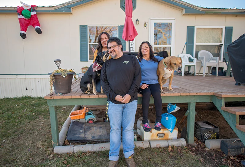 Laughter comes easily to the Armenta family as Joseph's dog, Bean, plants a kiss on his cheek. With Joseph are his mom and sister. The other dog is named Taquita. Multiple family members live close to one another in Farmington, N.M. After Joseph's heart transplant at age 35, he's appreciating simple moments at home that feel like a gift. Photo by Donovan Quintero, for UCHealth.