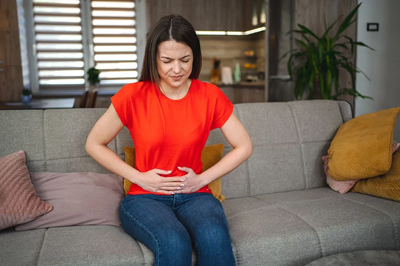Young woman holder her gut in pain. Colorectal cancer is rising in young people, and early symptoms can be easy to miss. Warning signs include changes in bowel habits, abdominal pain or rectal bleeding. Anyone with ongoing symptoms should talk with their health care provider. Photo: Getty Images.