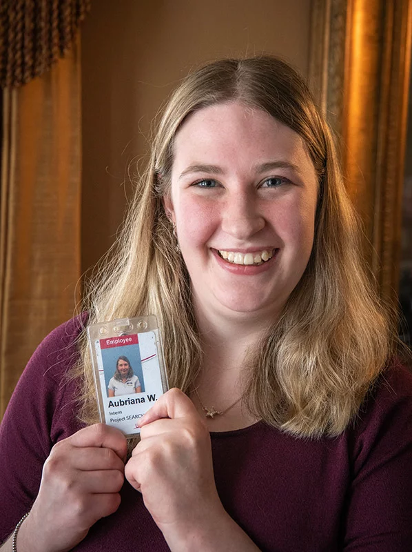 Aubriana, holding her UCHealth badge, takes pride in her job at Memorial Hospital Central. She's grateful for the chance to learn and work at the hospital that once helped her thrive. “I love being able to help people in any way I can," she said. Photo by Chuck Bigger, for UCHealth.
