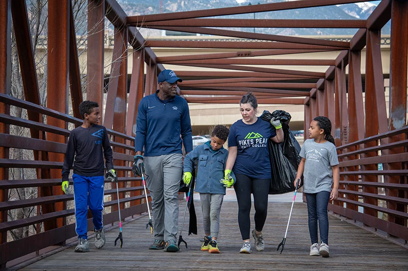 Mobolade, with his wife, Abbey Mobolade, and their three children, from left, Dawit, 12, Zion, 6, and Aletheia, 8, cross a pedestrian and bicycle bridge at America the Beautiful Park in downtown Colorado Springs after picking up trash at a community clean-up event. Photo by Chuck Bigger, for UCHealth.