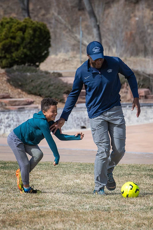 As his health crisis unfolded in summer 2025, Mobolade was forced to radically rethink his life: his health, his leadership style and his many relationships. Along the way, Mobolade would rethink his faith, too, and even his purpose. He now believes it’s his duty to share his story to encourage other people to take care of their health. After a community clean-up event on a recent Saturday, Mobolade kicked around a soccer ball with son Zion. Photo by Chuck Bigger, for UCHealth.