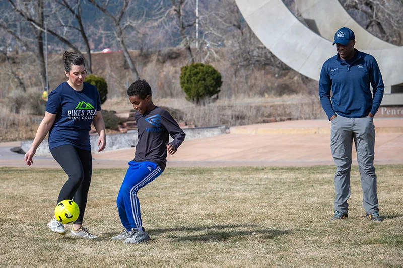 In May 2025, Abbey Mobolade noticed that her husband couldn't walk up a flight of stairs without pausing. He complained of pain in his chest. Trained as a nurse, she suspected pneumonia. “I had a gut feeling something wasn’t right. I remember looking at him on the couch and wondering, ‘Am I watching him go septic?’" She and their son, Dawit, enjoyed playing soccer after a recent community park clean-up event. Photo by Chuck Bigger, for UCHealth.
