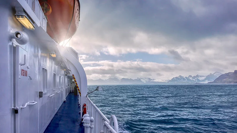 Dramatic and beautiful view of the snowcapped mountains of South Georgia Island on the horizon as seen from the deck of a ship.