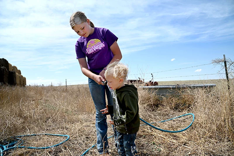 After filling the stock tank, Sadie gives Raeden a drink from the hose. Photo by Sonya Doctorian.
