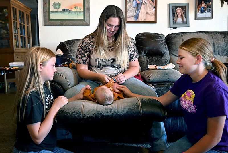 Jade dresses Beauden, while Kynlee Dunlap, 11, (left) and Sadie Jacquart, 10, hold his hands. Jade and her boyfriend, Branden Dunlap, didn't want to risk a birth at home or en route to the hospital and made plans to have Beauden at UCHealth Parkview Medical Center in Pueblo. Photo by Sonya Doctorian.