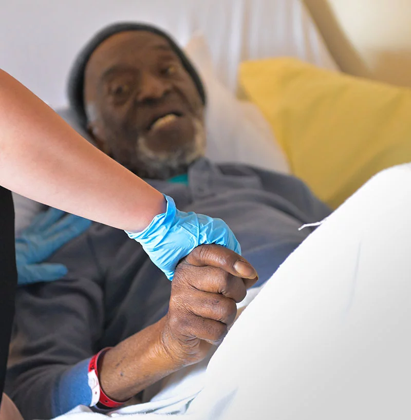 Caregiver Tawny Richardson holds James' hand while offering him food, drinks and a chance to watch westerns, which they both love. Photo by Cyrus McCrimmon, for UCHealth.