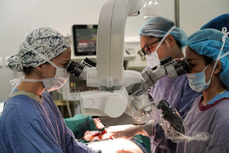 Dr. Taylor Allenby, a Colorado surgical resident, performs microsurgery as fellow resident Dr. Ariel Johnson assists with a Vietnamese colleague. The residents were part of an effort to expand surgical access by training local surgeons, while also gaining experience through global exchange. Photo courtesy of Dr. Mark Greyson.