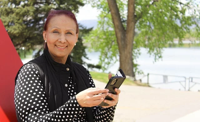 Claudia Rivas, a cancer patient, uses a journaling app on her phone to document her battle against metastatic cancer. Writing helps her process her emotions and find strength. Here, she stands overlooking Lake Loveland from the south shore, a place where she writes and reflects on the beauty around her. Photo: Ana Gretchen Robleto Lupiac, UCHealth.
