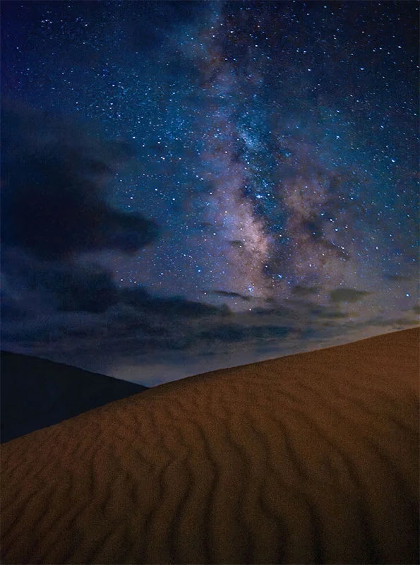 A colorful band of stars and light fill the sky above Great Sand Dunes National Park and Preserve. Photo by Patrick Myers, National Park Service.