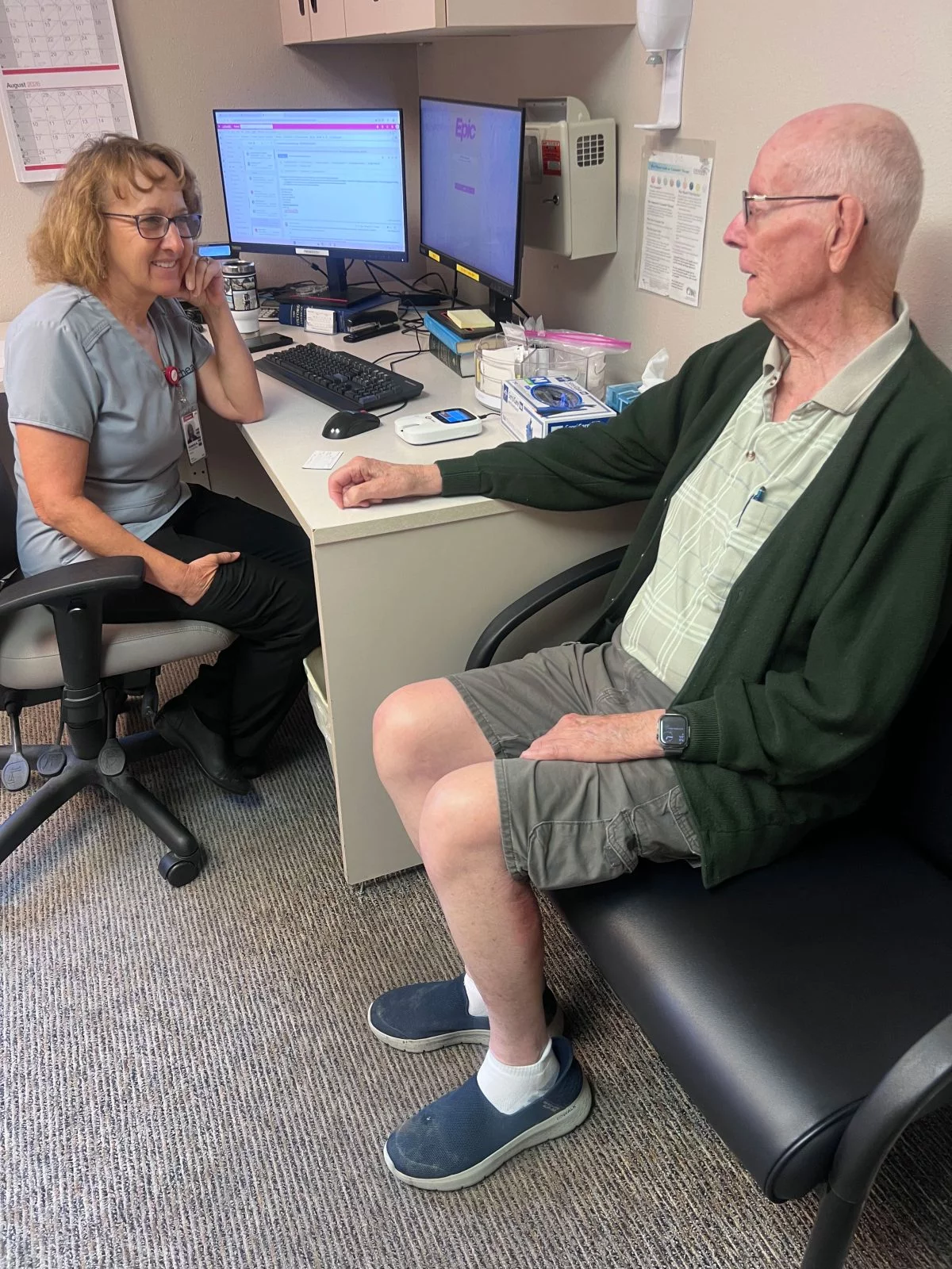 Kim Arline, a UCHealth pharmacist, sits with Ray White. Arline sees White regularly to monitor his blood clotting levels. On one office visit this spring, she encouraged him to participate in the Pueblo 150 Challenge, knowing how much he loves to walk. Photo by Joanna Bean, UCHealth.