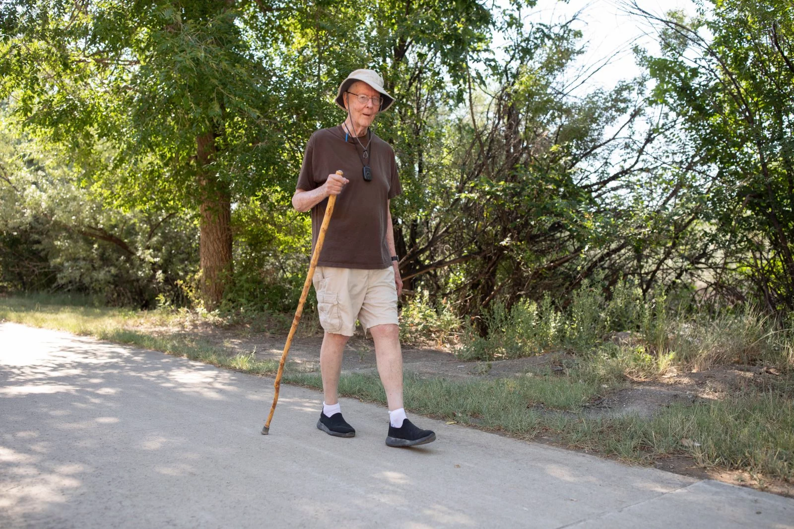 Ray White walking near The Pueblo Nature & Wildlife Discovery Center, one of his favorite places to walk. The trail features plenty of shade and views of the nearby Arkansas River. The Pueblo Nature & Wildlife Discovery Center is one of Ray White's favorite places to walk. The trail features plenty of shade and views of the nearby Arkansas River. Ray always carries his walking stick, logs his steps on his phone and wears his trademark hat and a fall monitor around his neck. Photo by Anslee Wolfe, for UCHealth.