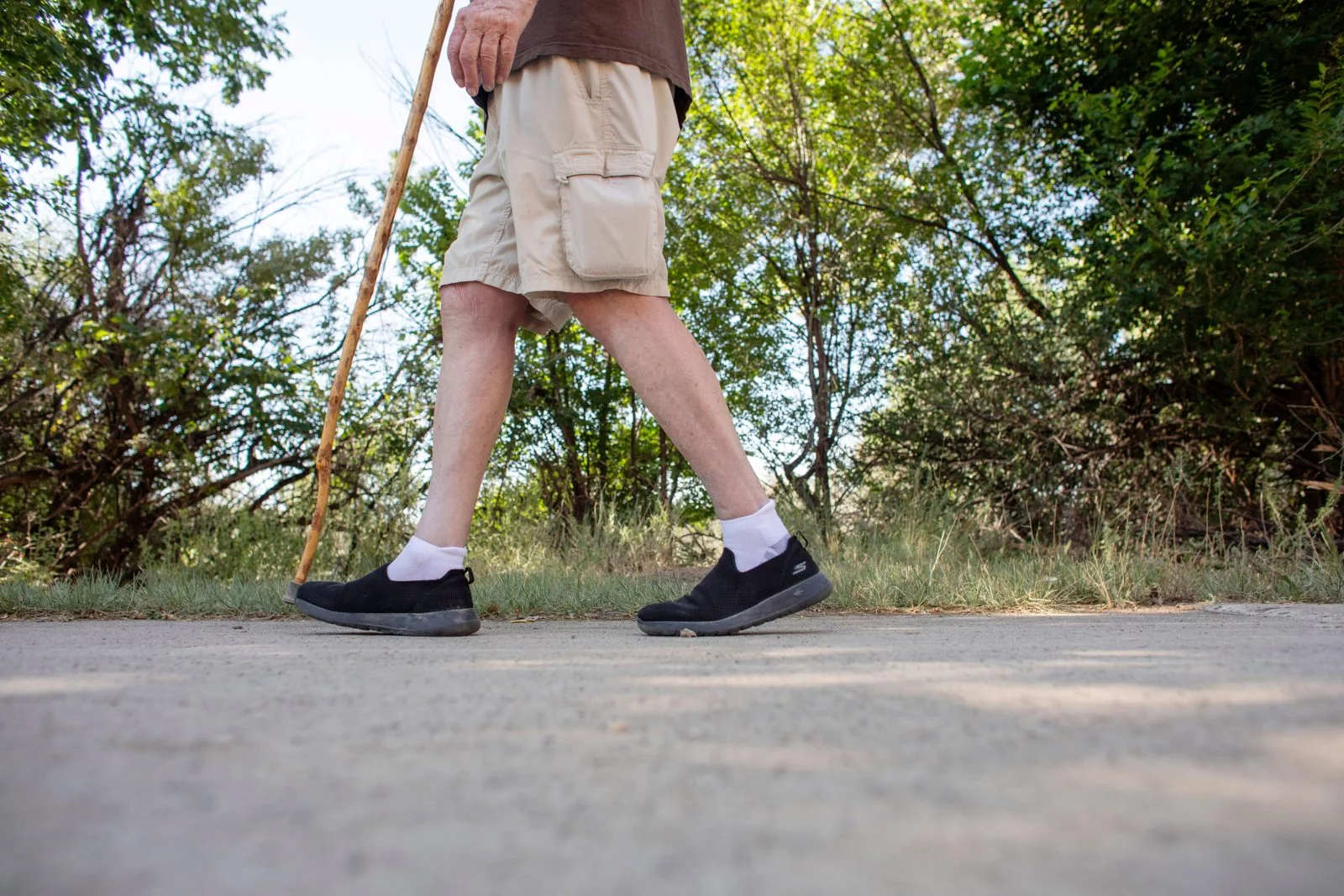 Ray's lower body and walking stick seen walking along a paved trail. Walking daily, staying busy with friends and listening to audiobooks keep White busy and engaged. Photo by Anslee Wolfe, for UCHealth.
