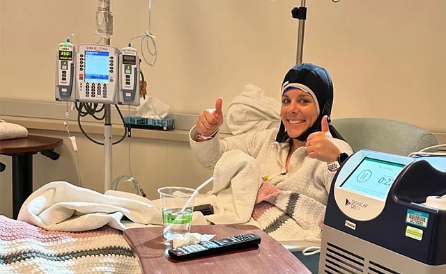 Karrissa wearing a cold cap and giving two thumbs up. To help save her hair during chemotherapy, Karissa Goossen used cold cap therapy while undergoing treatment for Stage 3 breast cancer. Photo courtesy of Karissa Goossen. 